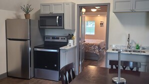 A compact kitchen with a refrigerator, microwave, stove, and sink. - The Corner Shed- Norris Lake or the Mountains (Jacksboro)