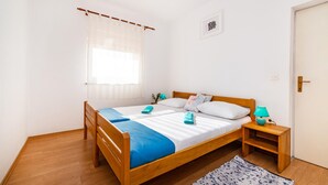 A single-bed room with a wooden frame, a window with sheer curtains, a bedside lamp, and a small bedside table. - 2 bedroom awesome apartment in Rovanjska (Rovanjska)