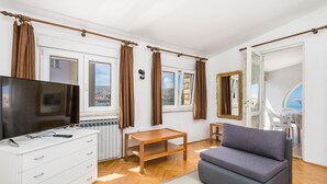 A modern living room with a flat-screen TV, white dresser, wooden table, and a grey sofa. - 2 bedroom lovely apartment in Pag (Pag)