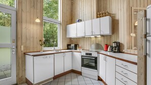 Een moderne keuken met witte kastjes, een inbouwoven en een koffiezetapparaat.
