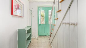 A narrow hallway with a green door, a staircase with wooden handrails, and a framed picture on the wall. - Beautiful home in Nerezine (Nerezine)