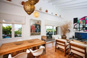 Enjoy meals and relaxation in this spacious living area with a dining table, sofa, and TV.