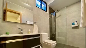 A modern bathroom with a glass-enclosed shower, a white toilet, and a vanity with a mirror and towel rack.