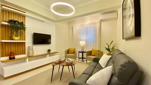 A modern living room with a sofa, a TV, a coffee table, and a plant.