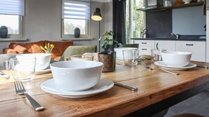 Un coin repas avec une table en bois, dressée avec des bols, des assiettes et des verres blancs.