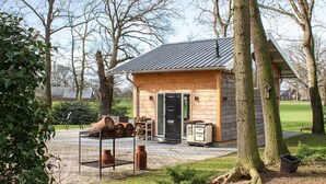 Une cabane en bois avec un toit en métal, une porte et une petite véranda comprenant une table et des chaises.