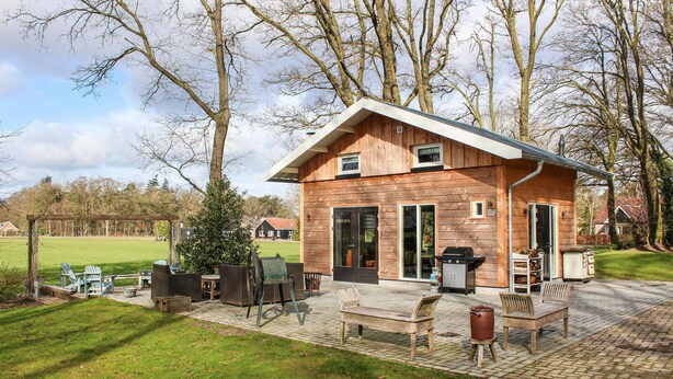 Une cabane en bois dotée d’un patio, d’un espace salon extérieur et d’un barbecue.