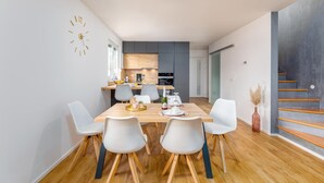 Una cucina moderna con mobili in legno, un'area pranzo con tavolo e sedie bianche, e una scala con gradini in legno.