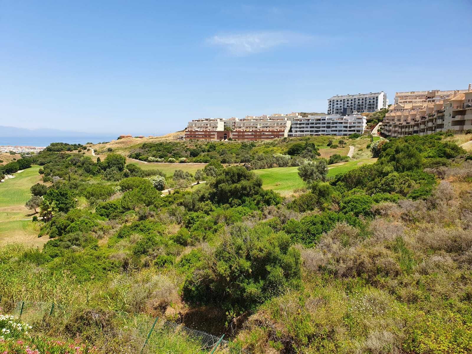A residential area with multiple apartment buildings, lush green landscapes, and a clear view of the sea.