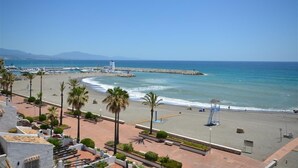 Une vue sur la côte, avec une plage, des palmiers et un poste de surveillance des sauveteurs.