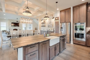 A modern kitchen with wooden cabinets, stainless steel appliances, and pendant lighting.