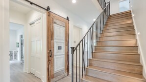 A staircase with wooden steps and metal railings, leading to a room with white walls and a door with a wooden frame.