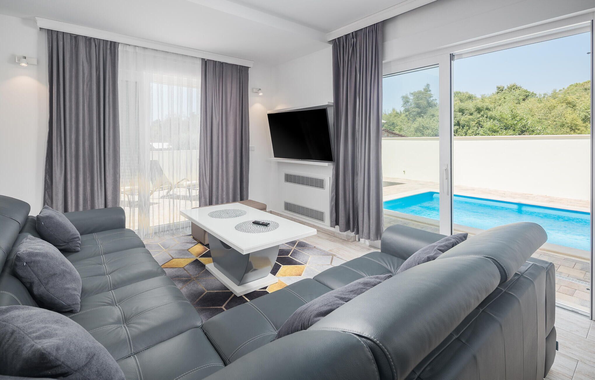 Ein modernes Wohnzimmer mit einem grauen Sofa, einem Couchtisch und einem Flachbildfernseher.