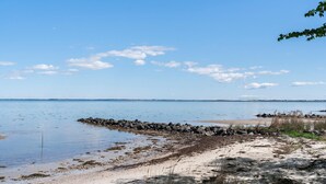 A beach with calm waters, a rocky shoreline, and distant land.
