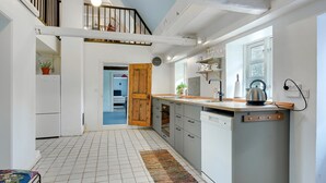 A modern kitchen with a built-in dishwasher, a kettle, and a window providing natural light.