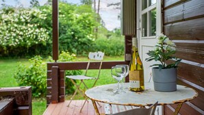 Een houten terras met een tafel, een fles wijn en een bloempot.