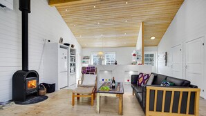 Een gezellige woonkamer met een open haard, houten meubels en een keukenhoek.