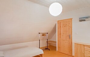 A room with a wooden floor, a white bench, a wooden door, and a wall-mounted light fixture. - 2 bedroom amazing home in Rowy (Rowy)