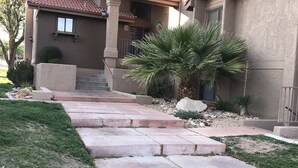 A two-story house with a red-tiled roof, a front porch, and a stone pathway leading to the entrance. - Greater Zion Villa at Sports Village (St. George)