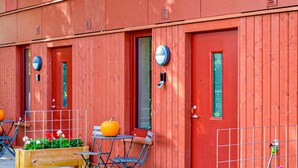 Una hilera de puertas de madera roja con pequeñas ventanas, cada puerta tiene un pomo metálico redondo.