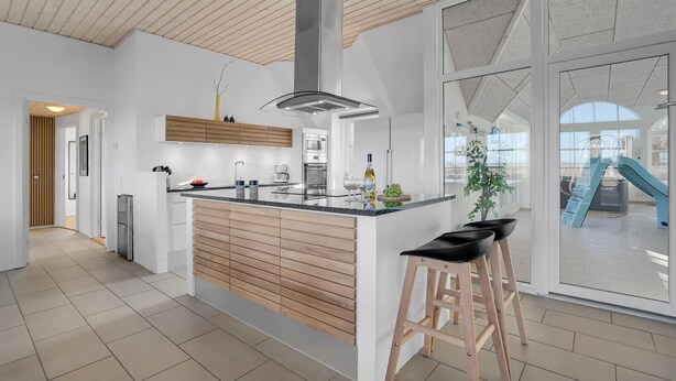 Une cuisine moderne dotée d’un îlot central, de meubles en bois et d’une grande fenêtre.