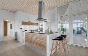 Eine moderne Küche mit Kochinsel, Holzschränken und einem großen Fenster.