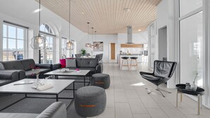 Un salon moderne comprenant un canapé, une table basse, des poufs et un coin repas avec des chaises.