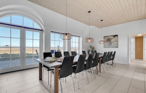 A dining area with a long table, chairs, and pendant lights.