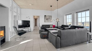Un salon moderne avec une cheminée, un grand téléviseur et un ensemble de canapés.