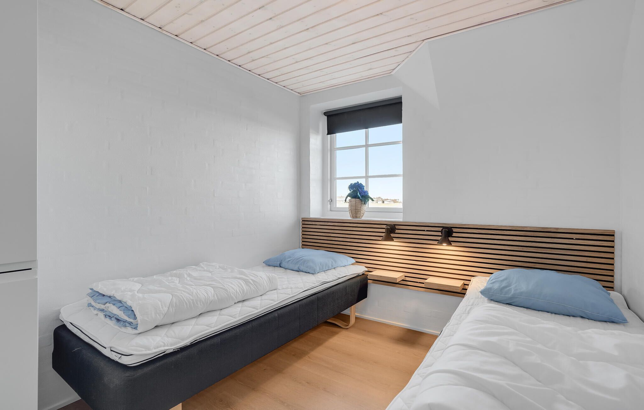 A small, clean room with two beds, a window with a view, and a wooden headboard.