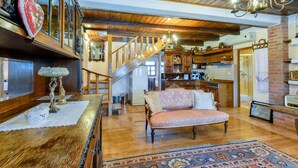 A spacious living room with a wooden staircase, a kitchen area, and a bathroom.