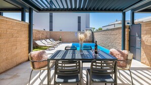 Un patio exterior con piscina, sillas de descanso y una mesa de comedor con sillas.
