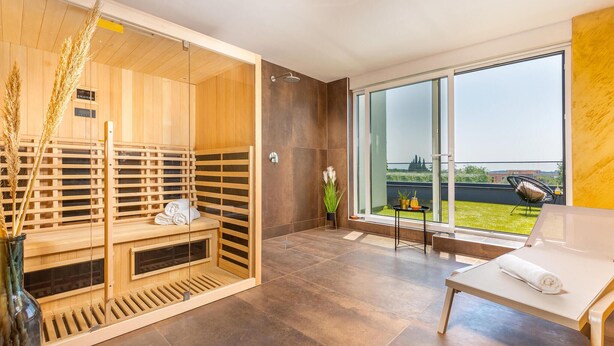 Una sauna moderna con bancos de madera, una puerta de vidrio que da a un balcón y vistas al exterior.