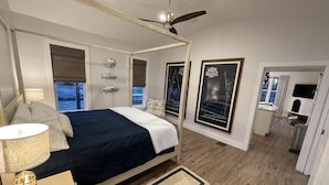 A bedroom with a bed, bedside lamp, and framed pictures on the wall.