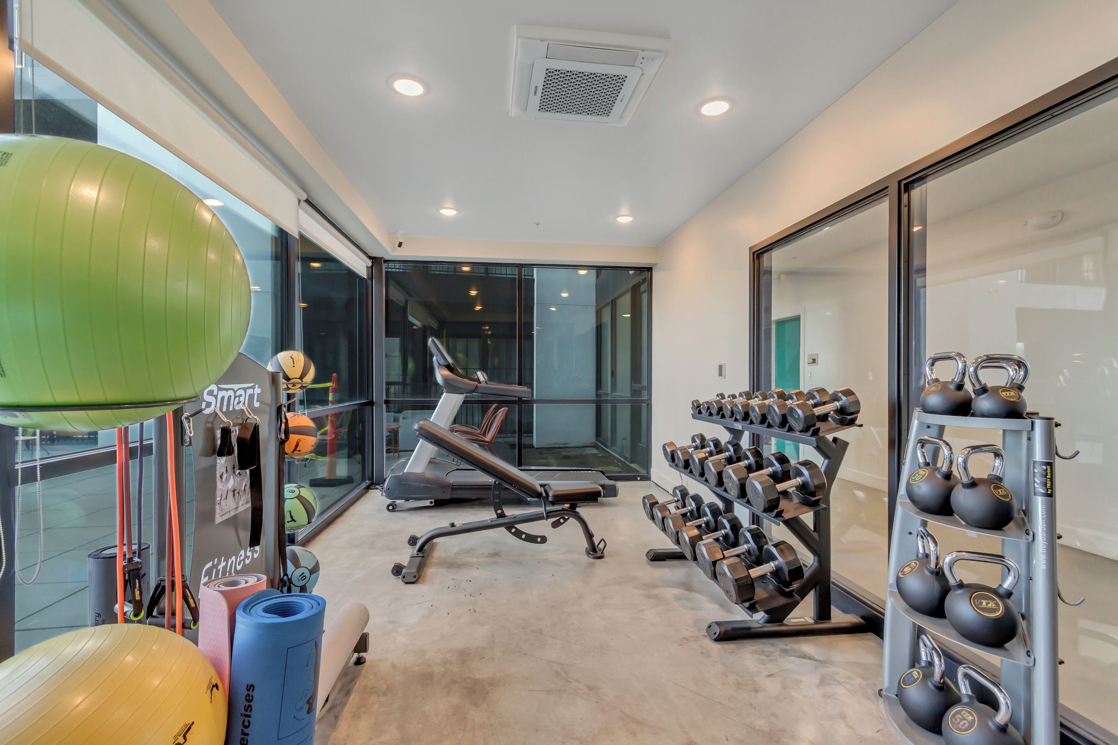 A gym with exercise equipment, a treadmill, and a wall-mounted dumbbell rack.