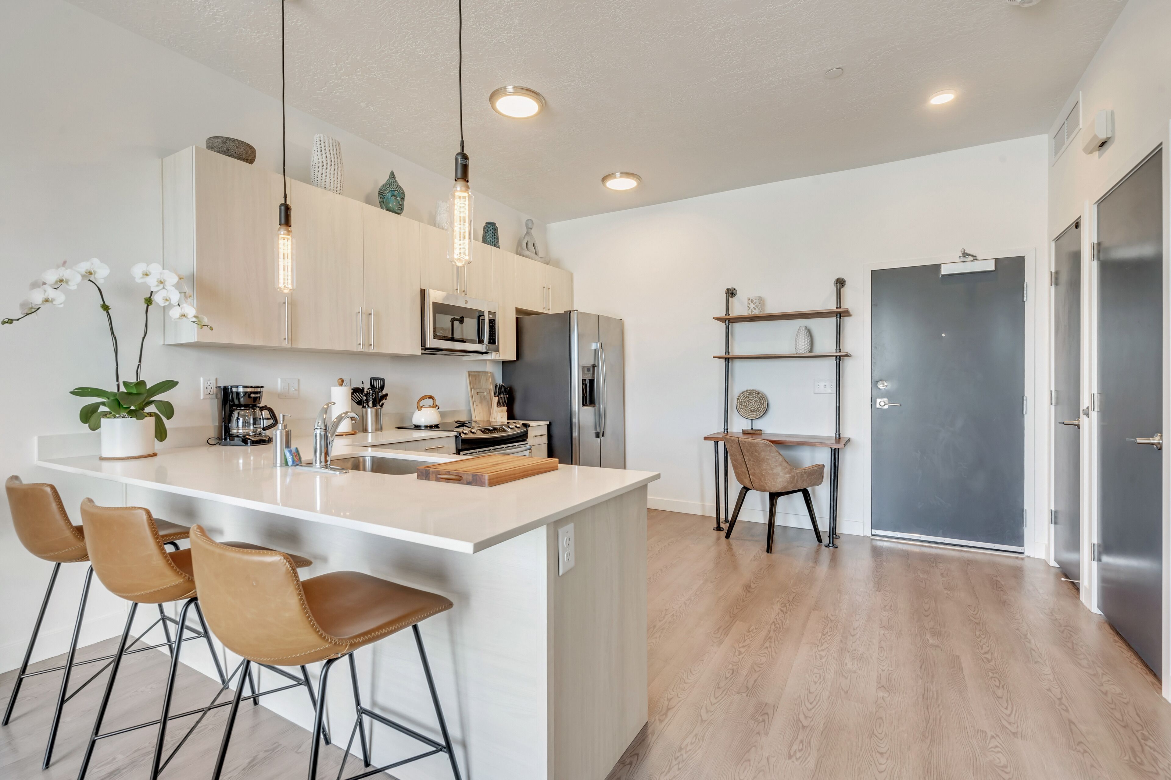 A modern kitchen with a central island, bar stools, and pendant lighting.