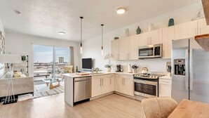 Una cocina moderna con armarios de madera clara, electrodomésticos de acero inoxidable y una isla central.