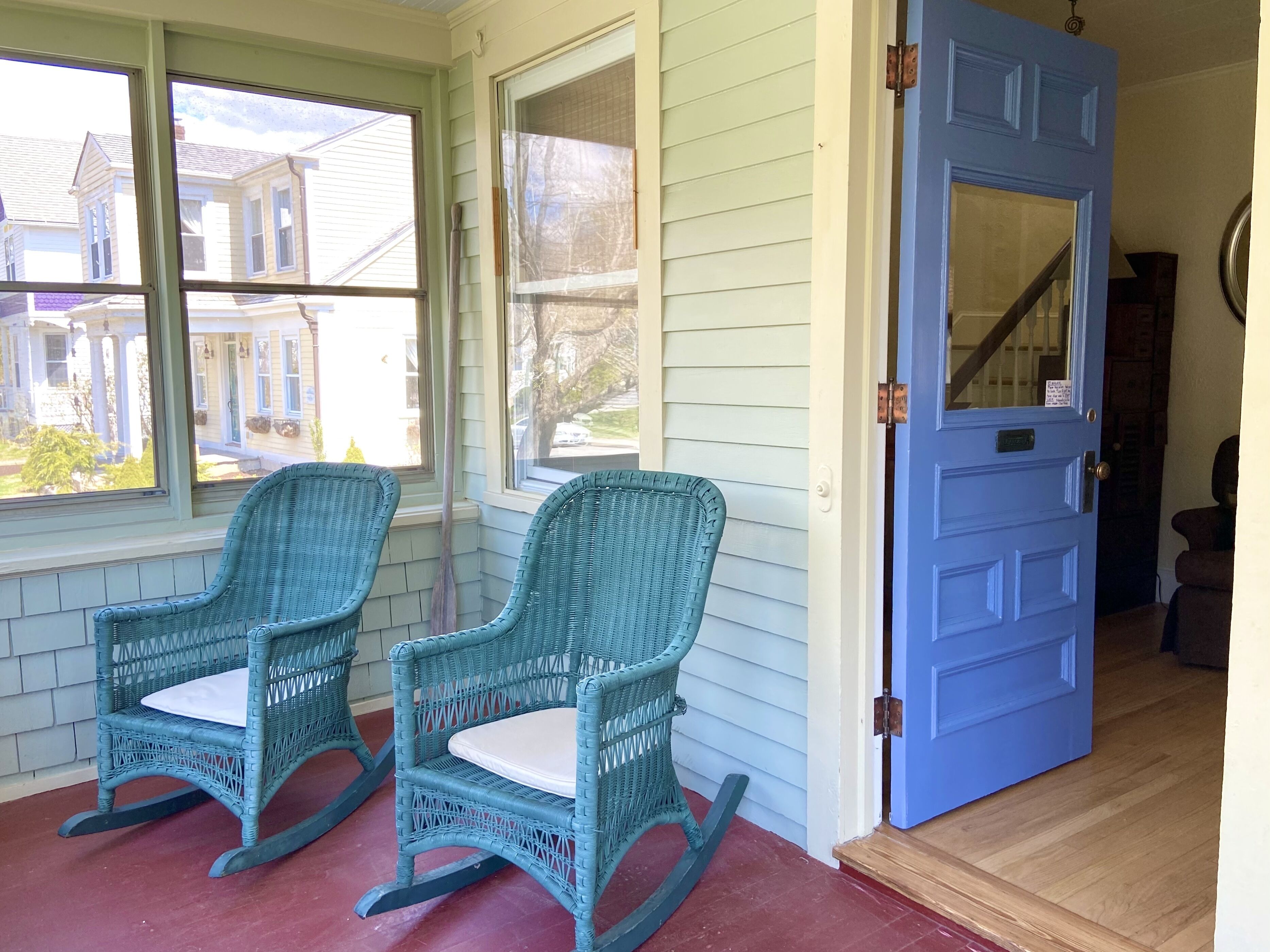 A porch with two rocking chairs and a blue door.