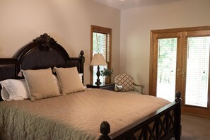 Un dormitorio con una cama grande, una mesita de noche, una lámpara, una silla y una ventana con persianas.
