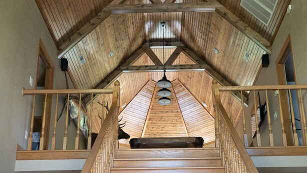 Een houten trap met een hoge plafond en een kroonluchter.