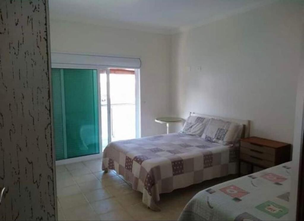 Ein Schlafzimmer mit einem Bett, einem Nachttisch, einem Sessel und einem Fenster.