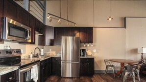 Una cocina moderna con electrodomésticos de acero inoxidable, armarios de madera oscura y un comedor con sillas de metal.