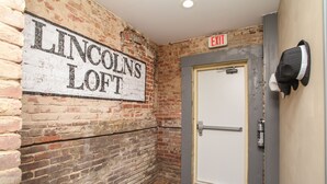 Un muro de ladrillo con un letrero que dice "Lincoln's Loft" y una puerta con un cartel de salida encima.