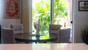 A modern dining area with a glass table, four chairs, and a decorative coral piece. A framed sign with text is on the wall, and a plant is visible in the corner. - 💎Luxury Home Away From Home! 🏝Beach🌞Sunshine🏌️‍♂️Golfing  (Waikoloa)