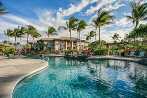 A swimming pool with lounge chairs and palm trees.