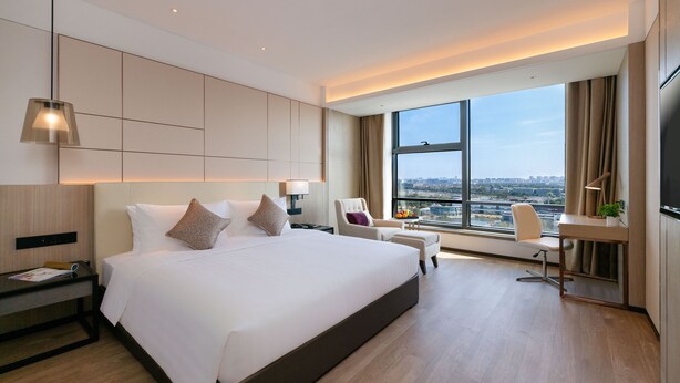 A modern hotel room with a large bed, a desk, a chair, and a TV. - Kew Green Hotel Hongqiao Shanghai (Shanghai)