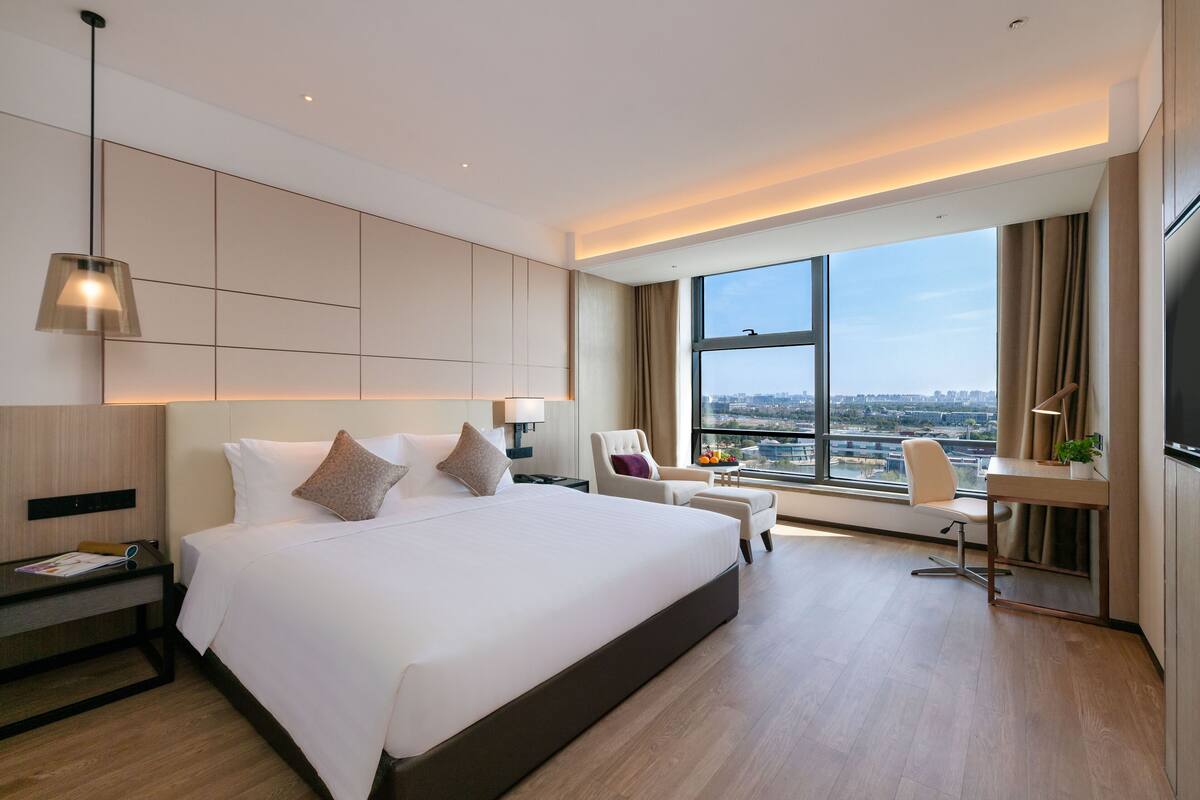 Une chambre d’hôtel moderne équipée d’un grand lit, d’un bureau, d’une chaise et d’un téléviseur.