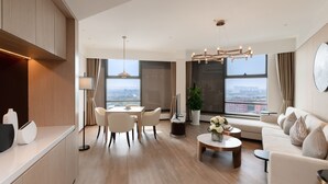 A modern living room with a dining area, large windows, and a view of the city. - Kew Green Hotel Hongqiao Shanghai (Shanghai)