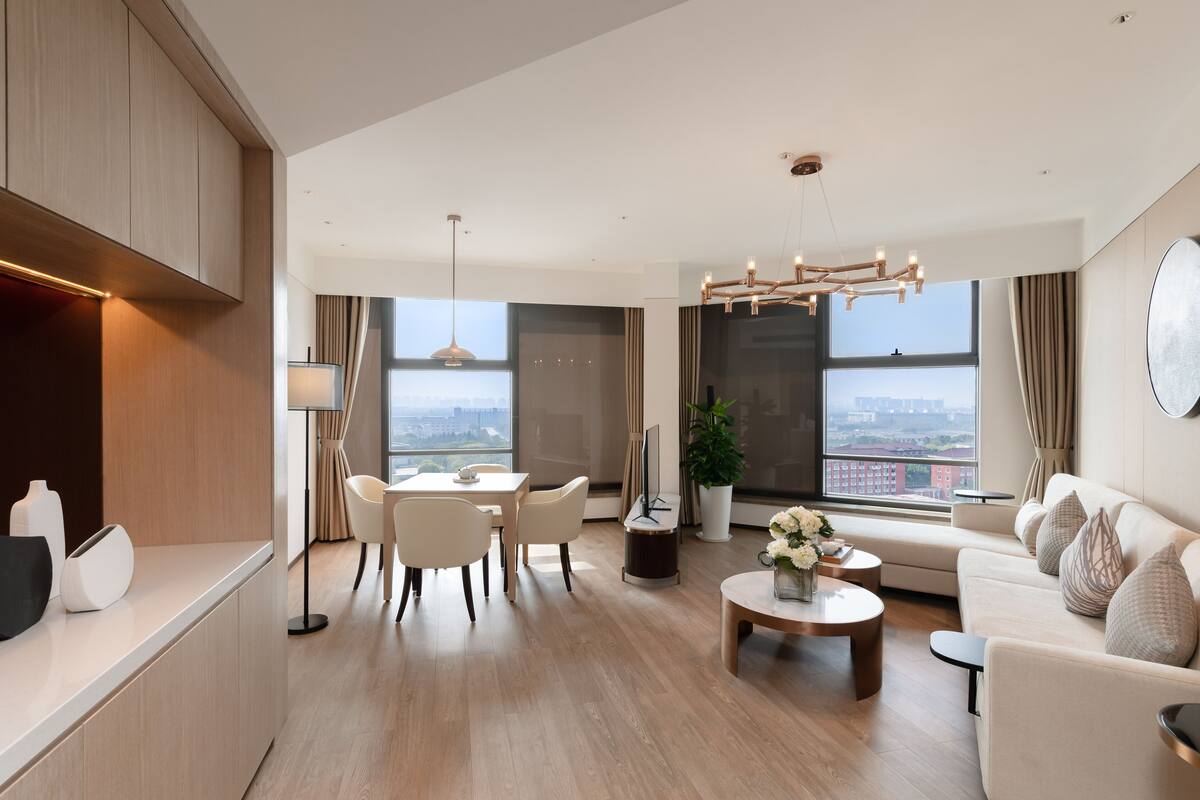 Un salon moderne avec un coin repas, de grandes fenêtres et une vue sur la ville.