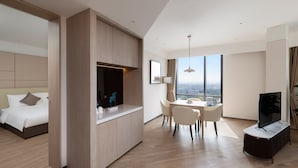 A modern hotel room with a bed, a dining area with a table and chairs, a TV, and a large window offering a city view. - Kew Green Hotel Hongqiao Shanghai (Shanghai)
